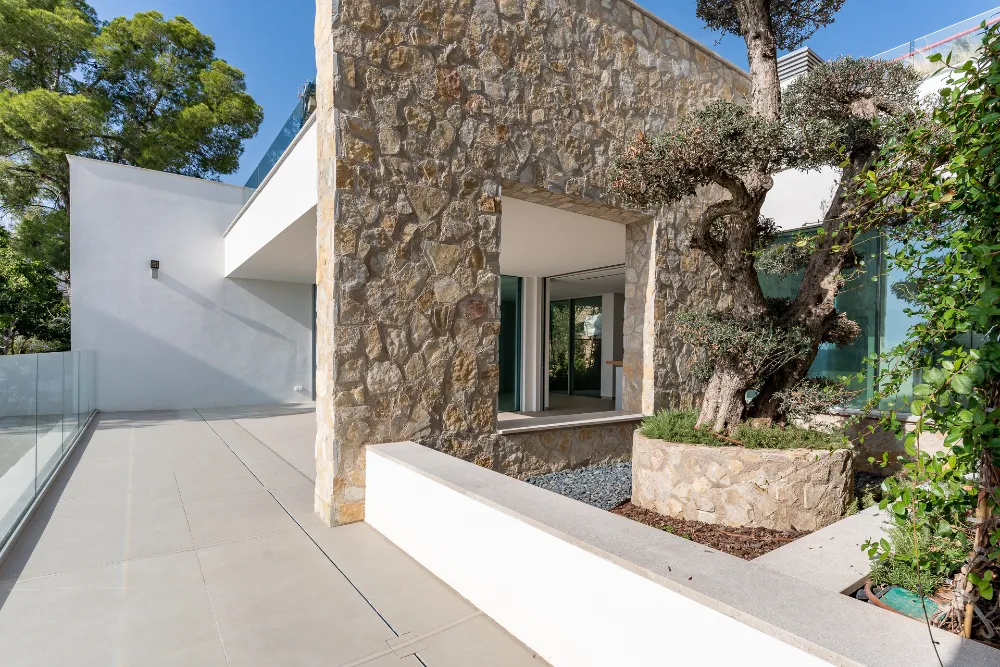 Villa entrance courtyard with stone arch, olive tree and landscaped garden