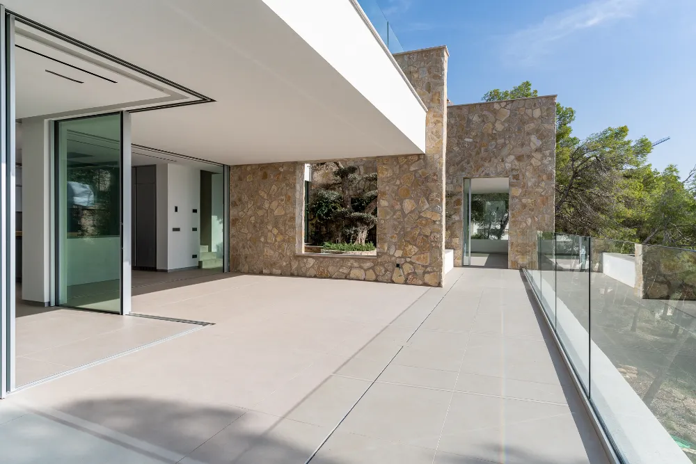 Open-plan kitchen and terrace with stone wall and garden outlook