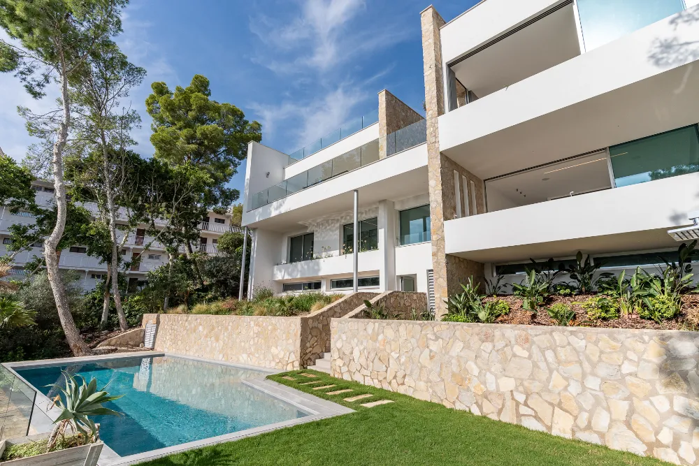 Modern white villa exterior with stone walls, terraces and swimming pool