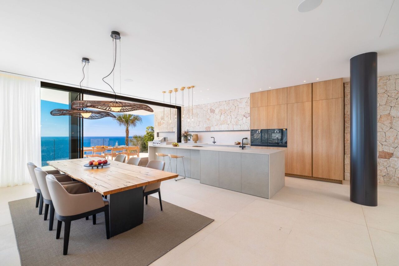 Open-plan kitchen and dining area with sea view and stone feature wall