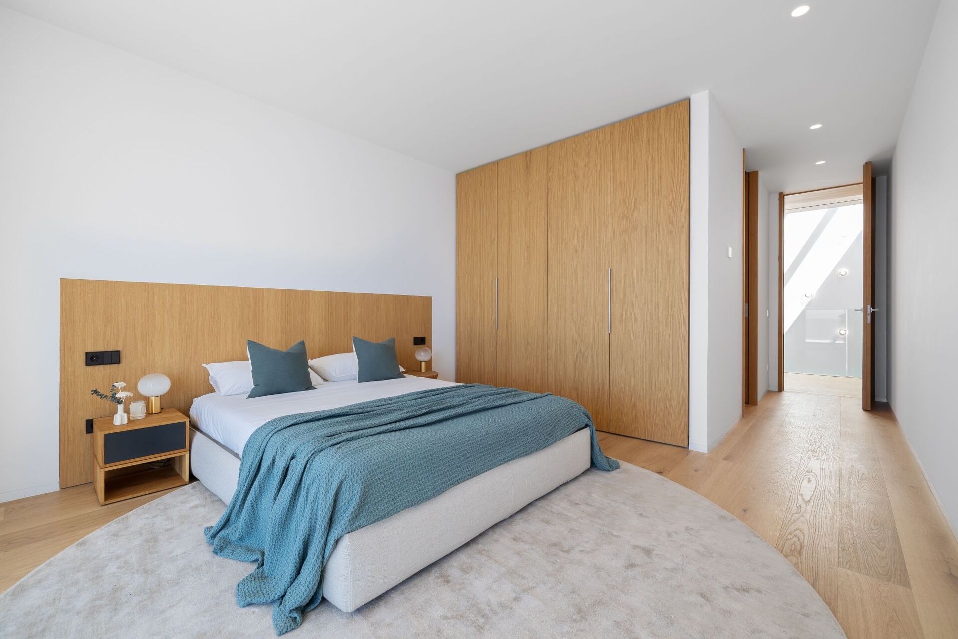 Contemporary bedroom with timber headboard, built-in wardrobes and sea view